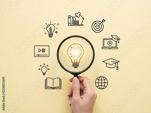 Hand holding magnifying glass over brain light bulb icon surrounding education online learning business icons concept