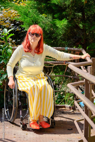 model with bright hair in yellow clothes posing while sitting in a wheelchair