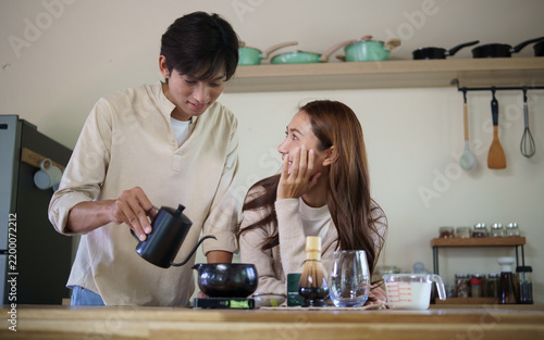 Fotografie Young Asian couple pouring water and preparing matcha tea at home