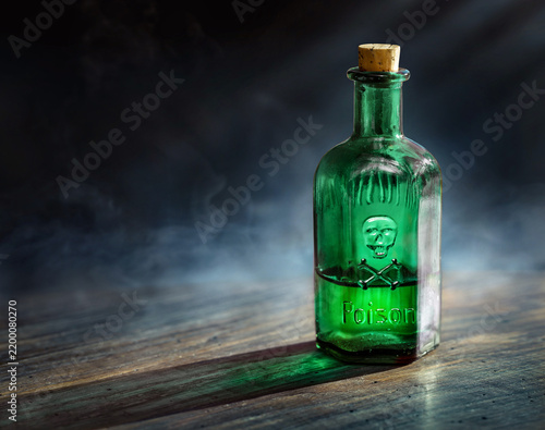 Glass poison bottle with skull and bones. Danger sign, symbol of death. Concept background on poison poisoning, pharmaceutical, chemistry, medical topic. Poison, venom, toxin, toxic background.