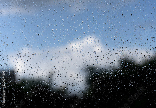 Raindrops streak a window, blurring the view