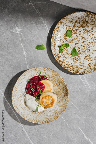 Obraz na płótnie Golden cottage cheese pancakes with cherry compote, sour cream and mint on a spe