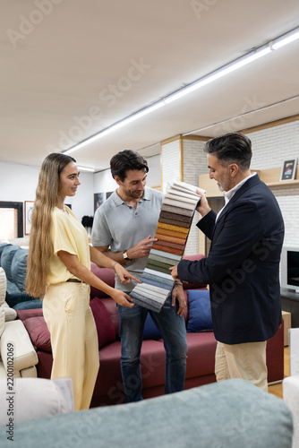 Couple selecting fabric swatches for new sofa with assistance from a salesman