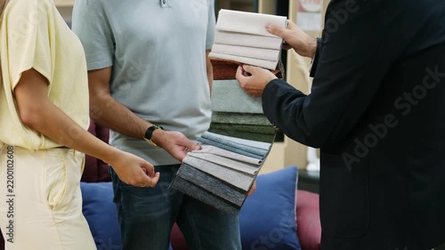 Young couple choosing upholstery fabric from a color swatch catalog in a furniture store
