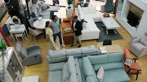 Salesman consulting a young couple buying a sofa in a large furniture showroom