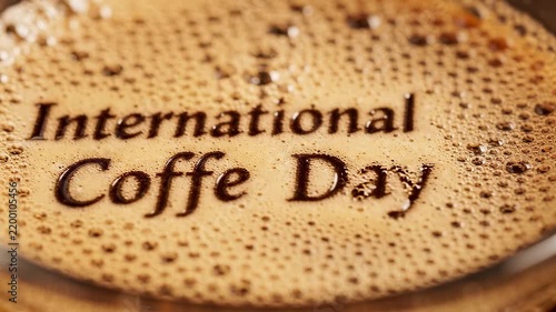 Close-up of a cup of espresso coffee foam with the text International Coffee Day written on the bubbly surface