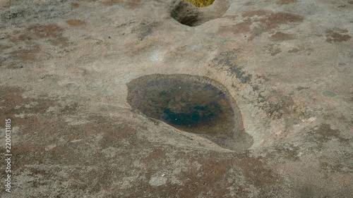 Natural rock basin with rainwater on weathered granite surface. Erosion carved stone texture and ancient geological formation. Granite bedrock detail with natural water pool and rugged landscape