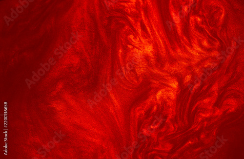 Shimmering red abstract background. Liquid glitter paint texture waves and swirls. Beautiful shiny red glitter texture. Metallic paint close-up as a holiday background.