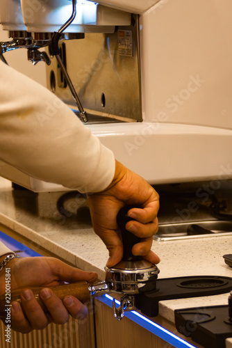 Foto Barista tamping coffee grounds into a portafilter, preparing espresso