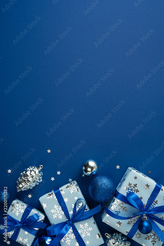 Obraz premium Blue Christmas presents with ribbons and ornaments for Merry Christmas and Happy New Year on vertical navy blue copyspace