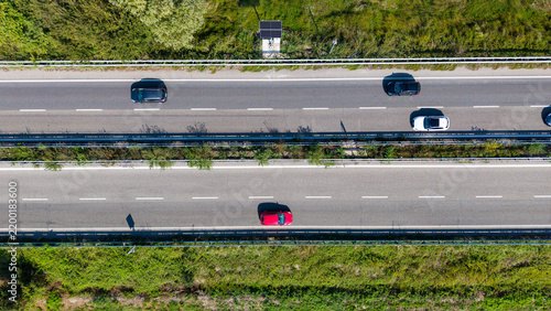 Картината върху платно Highway Traffic from Above: An aerial view captures a busy highway with several cars driving in multiple lanes, surrounded by green vegetation on the sides