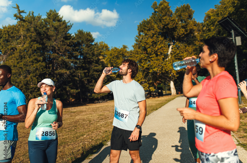 Obraz premium Runners taking a break to drinking water during marathon event.