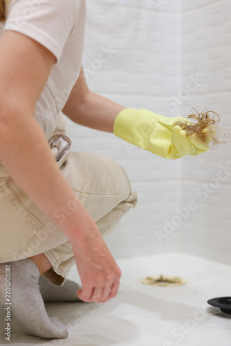 Cleaning hair from a clogged shower drain, ideal for plumbing services, drain cleaners and home maintenance content.