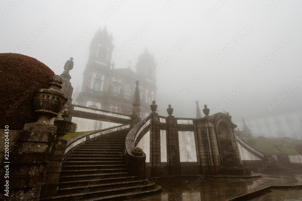 Fototapeta premium Foggy historic cathedral with a monumental stone staircase in Braga, Portugal