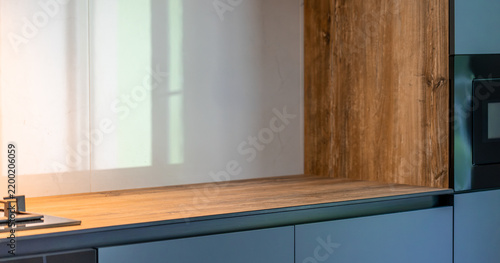 Wood countertop and blue kitchen cabinets. Modern interior with clean empty workspace.