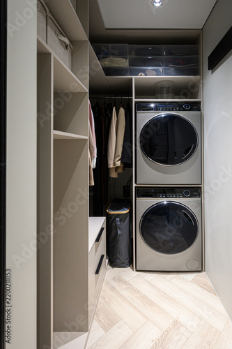Quadro su tela Compact laundry zone features stacked washer-dryer unit, open shelving, hanging
