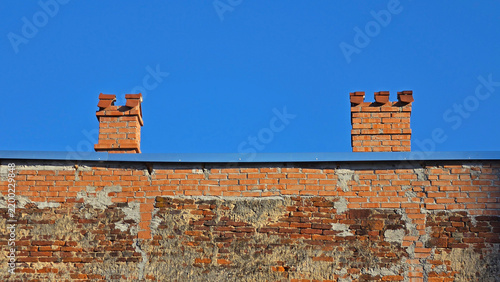 Foto Weathered red brick building wall and two decorative chimneys on a sunny day
