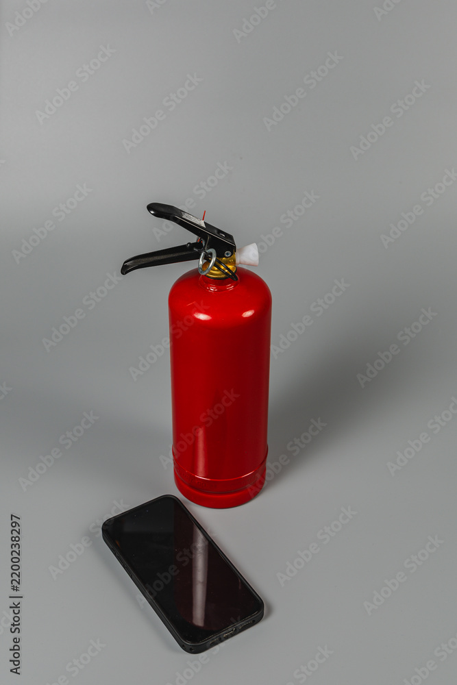 Obraz premium Fire extinguisher and smartphone placed on a gray surface