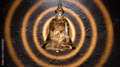 Crystal Glass Bell Ringing With Glowing Golden Sound Waves Emitting Outward in Dark Moody Setting