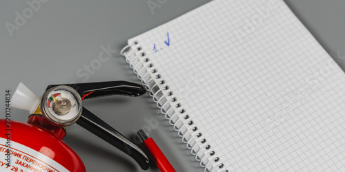 Fire extinguisher and notebook on a flat surface for safety inspection