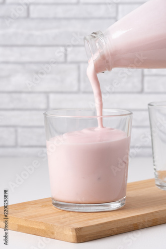 Cuadro en lienzo Pouring homemade fruit kefir, buttermilk or yogurt with probiotics