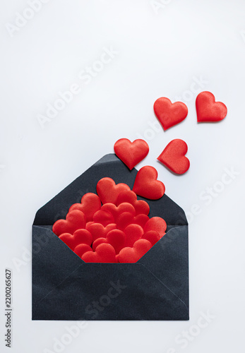 Obraz na płótnie A black envelope filled with red hearts releases several hearts upward