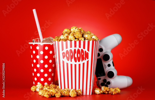 Foto Popcorn, cola and gamepad on red background