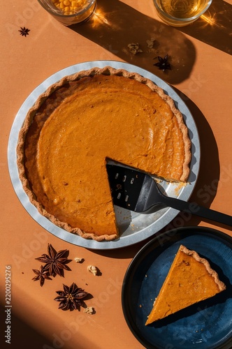 Pumpkin Pie on a Table With a Slice Removed and a Spatula for Serving