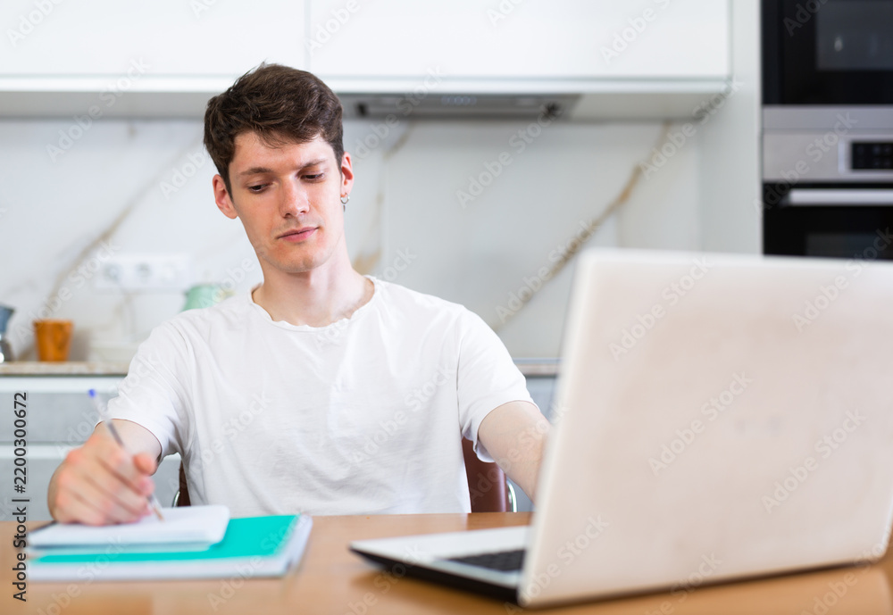 Fototapeta premium Young guy studying at home with laptop