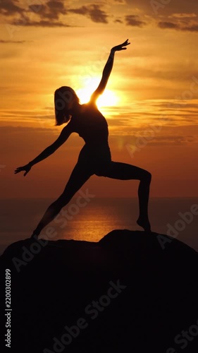 Woman Practicing Yoga Silhouette on Rocky Cliff at Golden Sunset