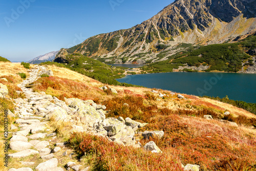 A hiking path and Wielki Staw Polski lake in Dolina Pieciu Stawow Polskich (The Valley of Five Polish Lakes) in High Tatras mountains. Zakopane, Malopolska, Poland.