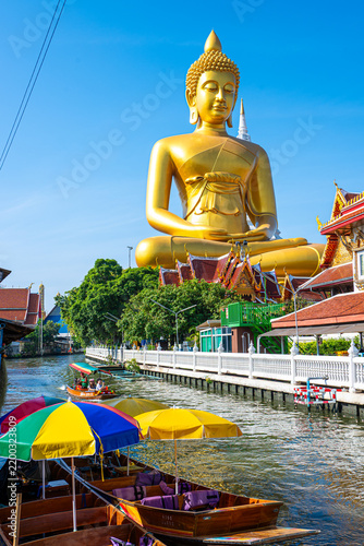 Longtail wooden boat travel at Giant Golden Buddha in Wat Paknam Phasi Charoen Temple on Chao Phraya River