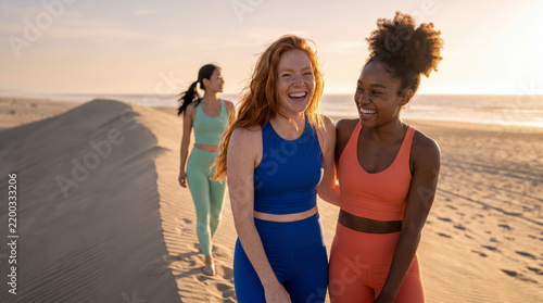Two friends laugh warmly together while a third walks along the beach dune
