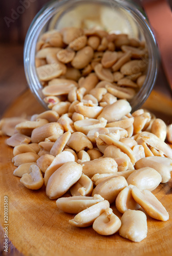 Peanuts spilling from jar with potato chips and rosemary