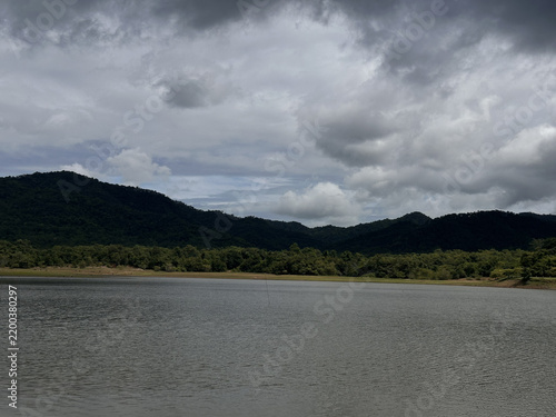 Reservoir landscape with layered mountains and overcast sky