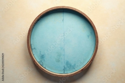 Circular tray with light blue surface and wood frame on beige background