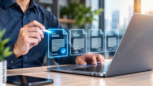 Businessman using a laptop while reviewing digital document files on holographic interface, symbolizing electronic data management and office automation