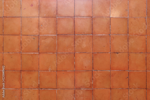 Full frame overhead view of aged square terracotta tiles with weathered glaze and grout joints creating a warm rustic background.