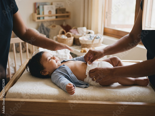 Parent Gently Changing a Baby's Diaper on a Nursery Changing Pad