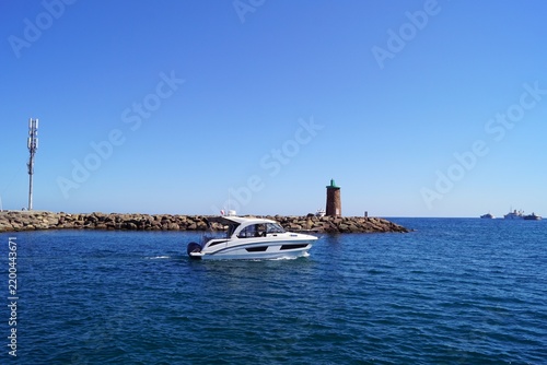 Motorboat near Mediterranean lighthouse and coastal mountain