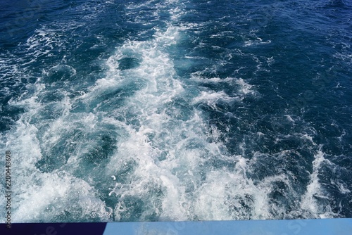 Boat wake creating white foam on deep blue sea