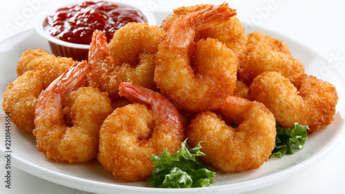 Crispy fried shrimp on a white plate with a side of ketchup, isolated on white background