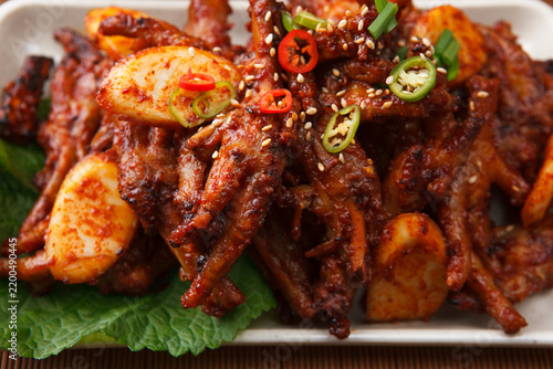 Spicy stir fried chicken feet with rice cake garnished with sesame and chili