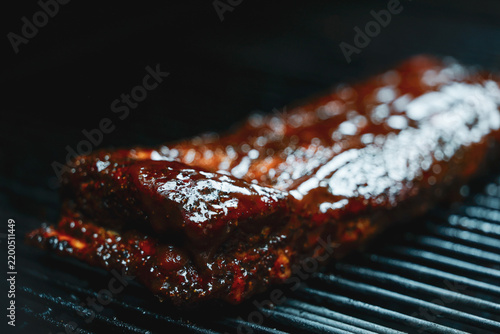 Barbecue pork ribs smothered in homemade bbq sauce smoking on a pellet grill smoker for dinner. 