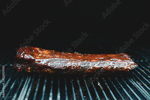 Barbecue pork ribs smothered in homemade bbq sauce smoking on a pellet grill smoker for dinner. 
