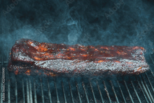 Barbecue pork ribs smothered in homemade bbq sauce smoking on a pellet grill smoker for dinner. 