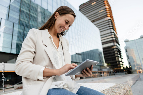 Professional woman smiling using digital tablet in urban setting