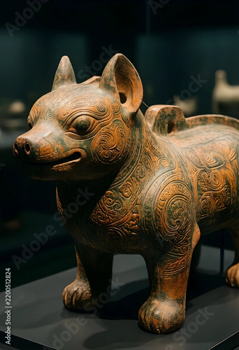 Ancient history and cultural heritage, ornate ceramic dog sculpture from pre-columbian civilization displayed in a museum exhibit with dark background