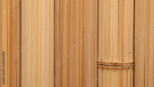 A close-up view of natural light brown bamboo poles arranged vertically.