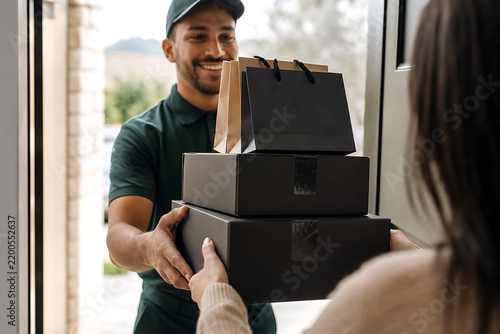 Delivery man giving black parcels and shopping bags to female customer at door, lifestyle style